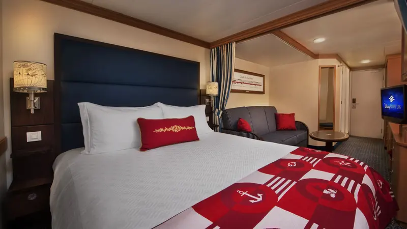 Cabine com cama de casal, cortinas, sofá e televisão